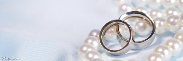 Zwei Eheringe liegen auf Perlen